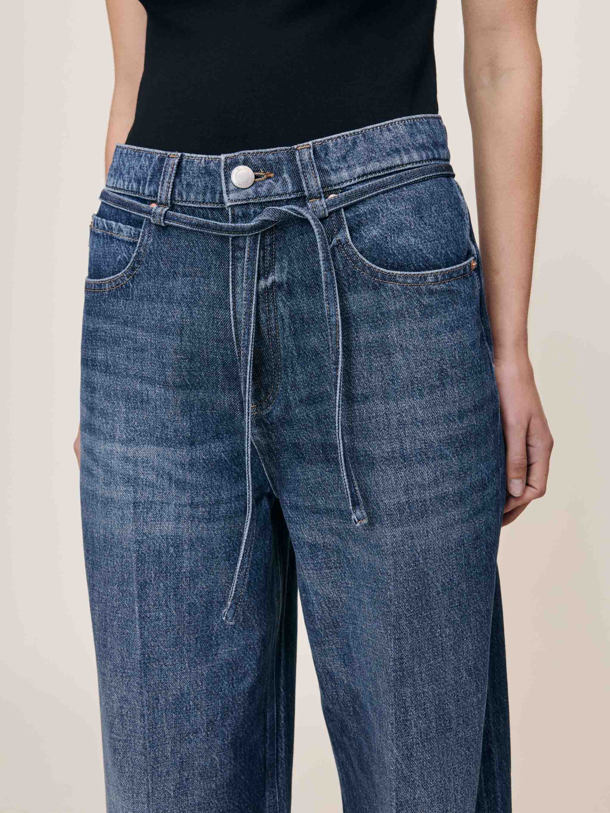 Blue jeans with a belt on a plain background