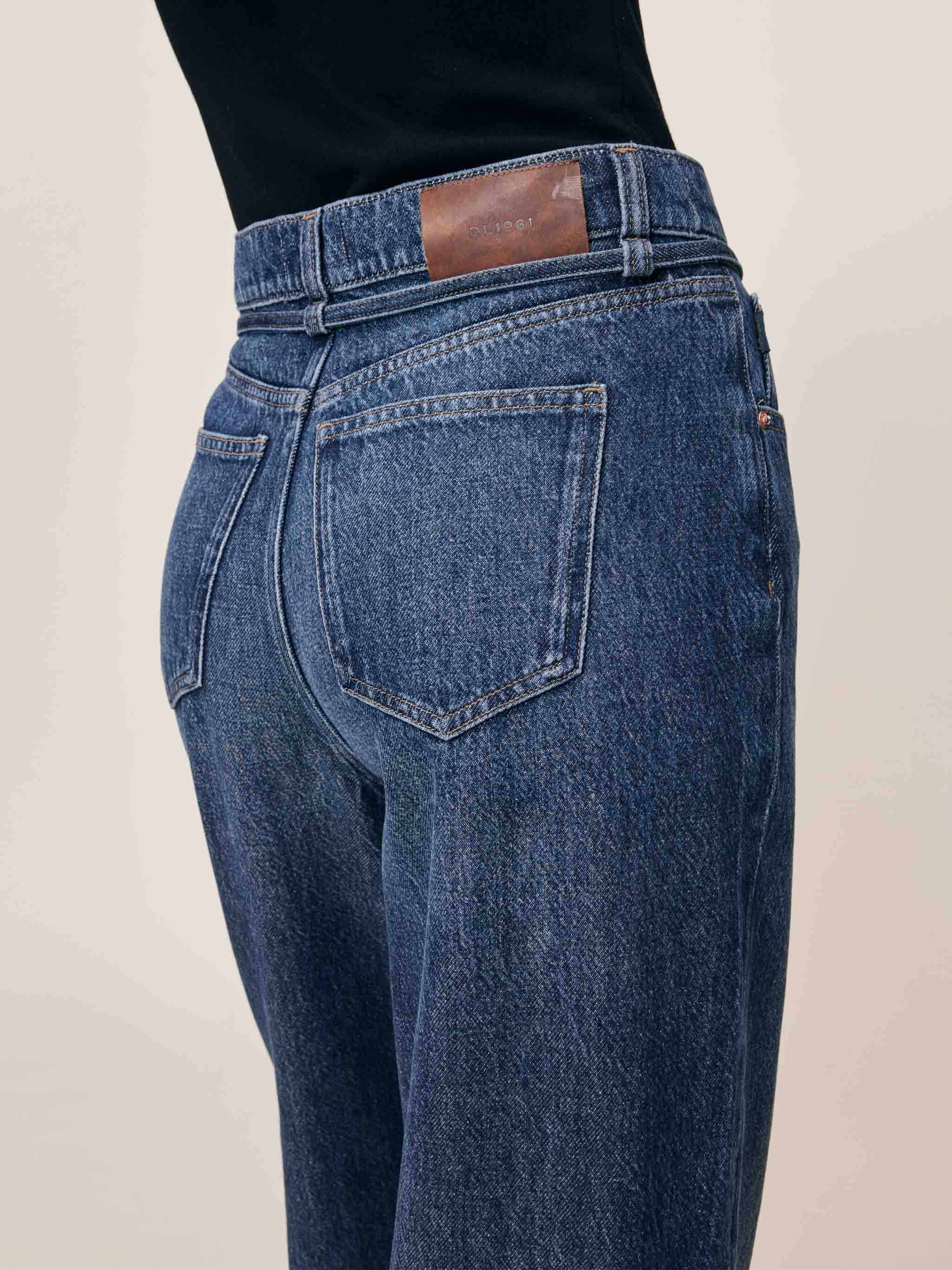 Blue jeans with a brown leather patch on a beige background
