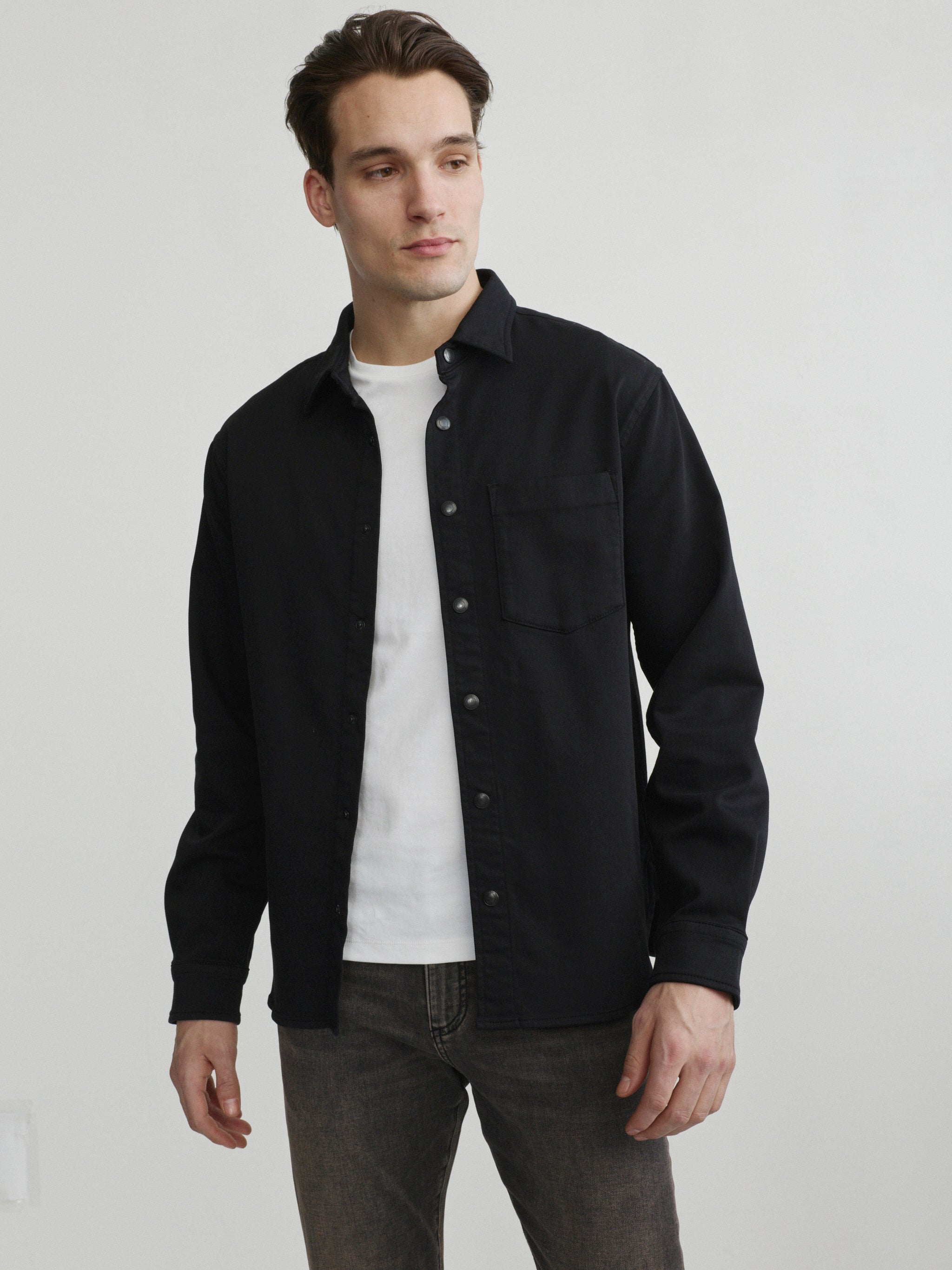 DL1961 men's Russell slim-straight jeans in washed grey-brown 'Rock', waist-up front view with black overshirt and white tee