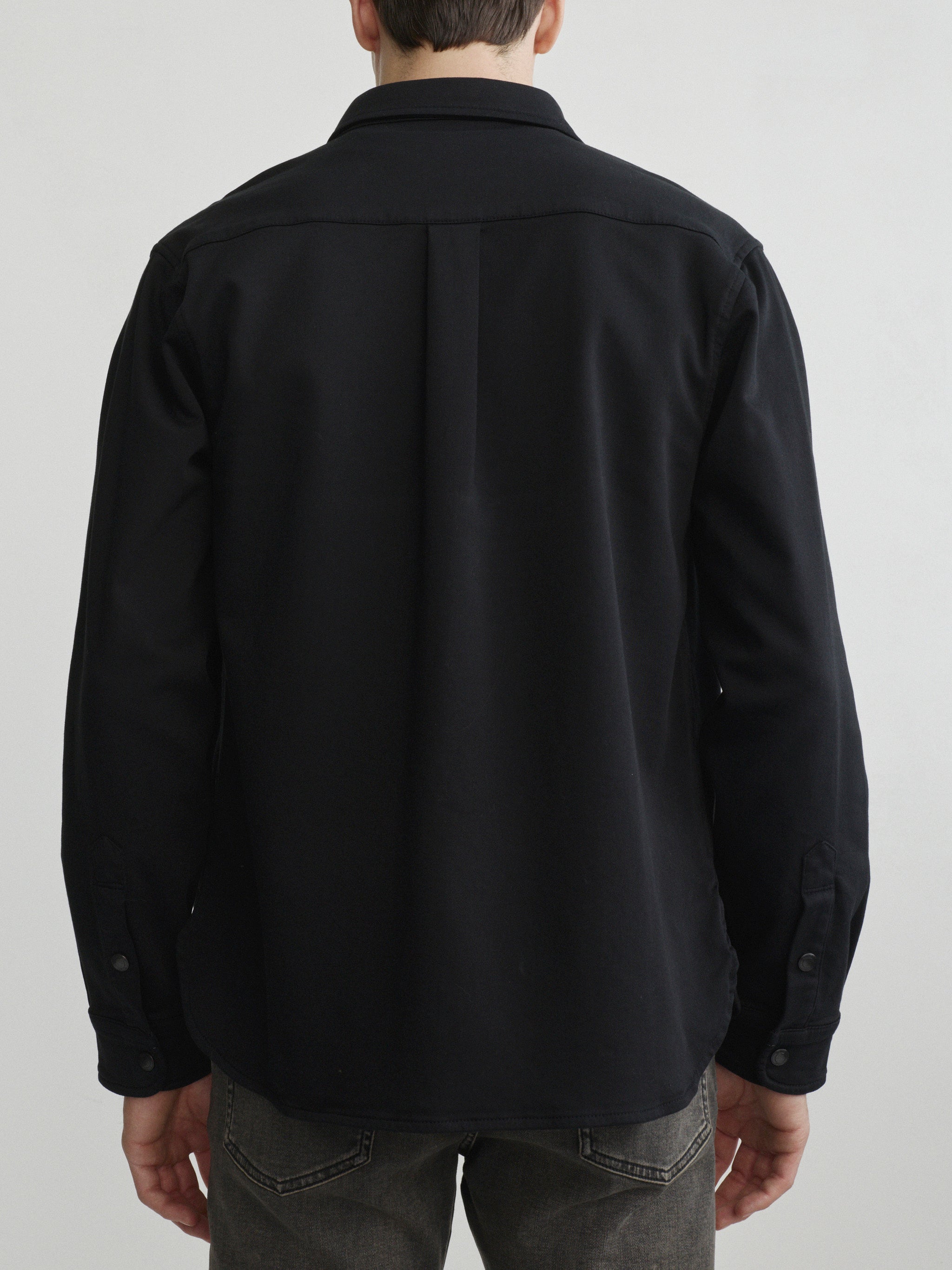 DL1961 men's Russell slim-straight jeans in washed grey-brown 'Rock', waist-up back view with black overshirt