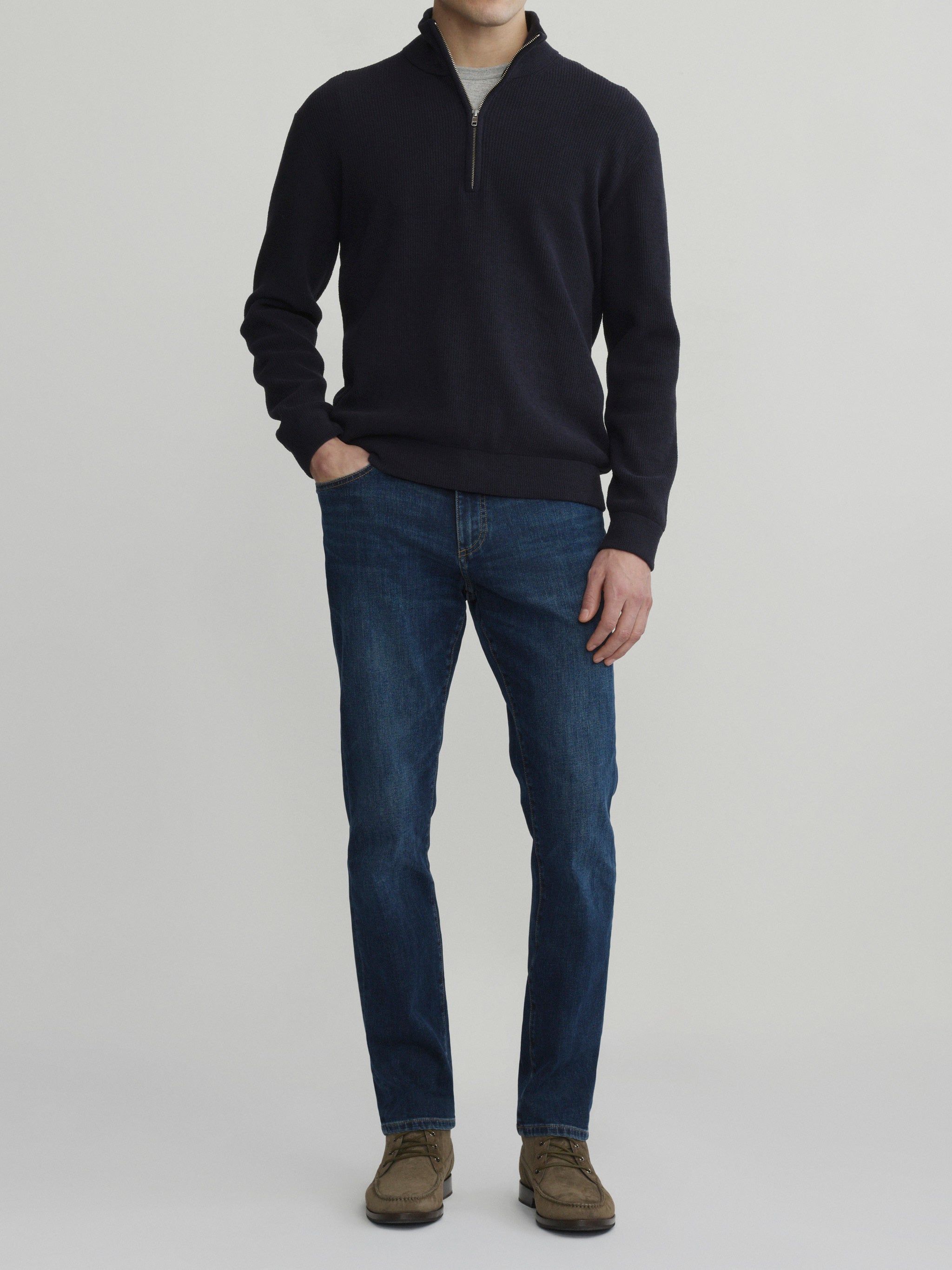 DL1961 men's Nick slim jeans in dark indigo 'Reader', front full-length view with navy quarter-zip sweater, hands in pockets